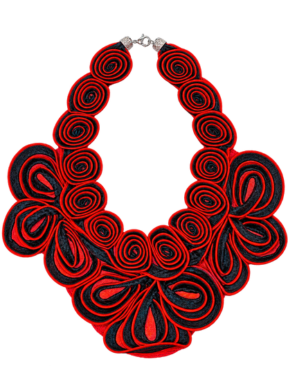 A bold statement bib necklace featuring layered red and black rolled fabric petals, with a silver-tone clasp at the top, shown against a plain white background.